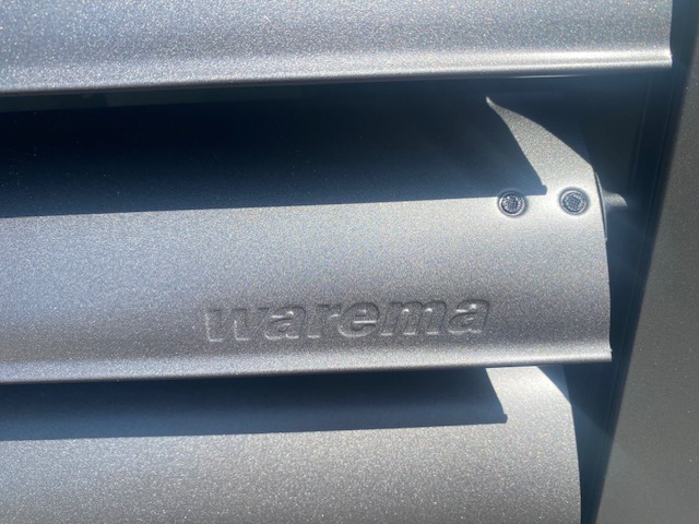 Close-up of a Warema external venetian blind slat showing the branded aluminium finish